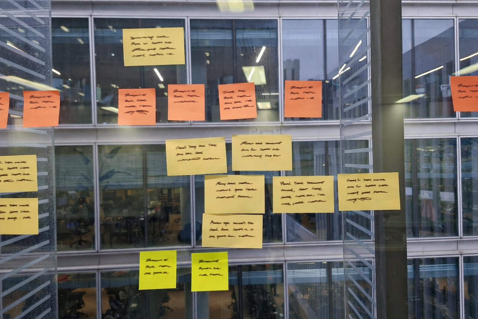 Post-it notes on a glass wall from an ideation workshop